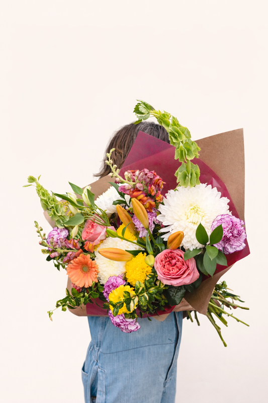 Person holding a colorful bouquet of flowers against a white background