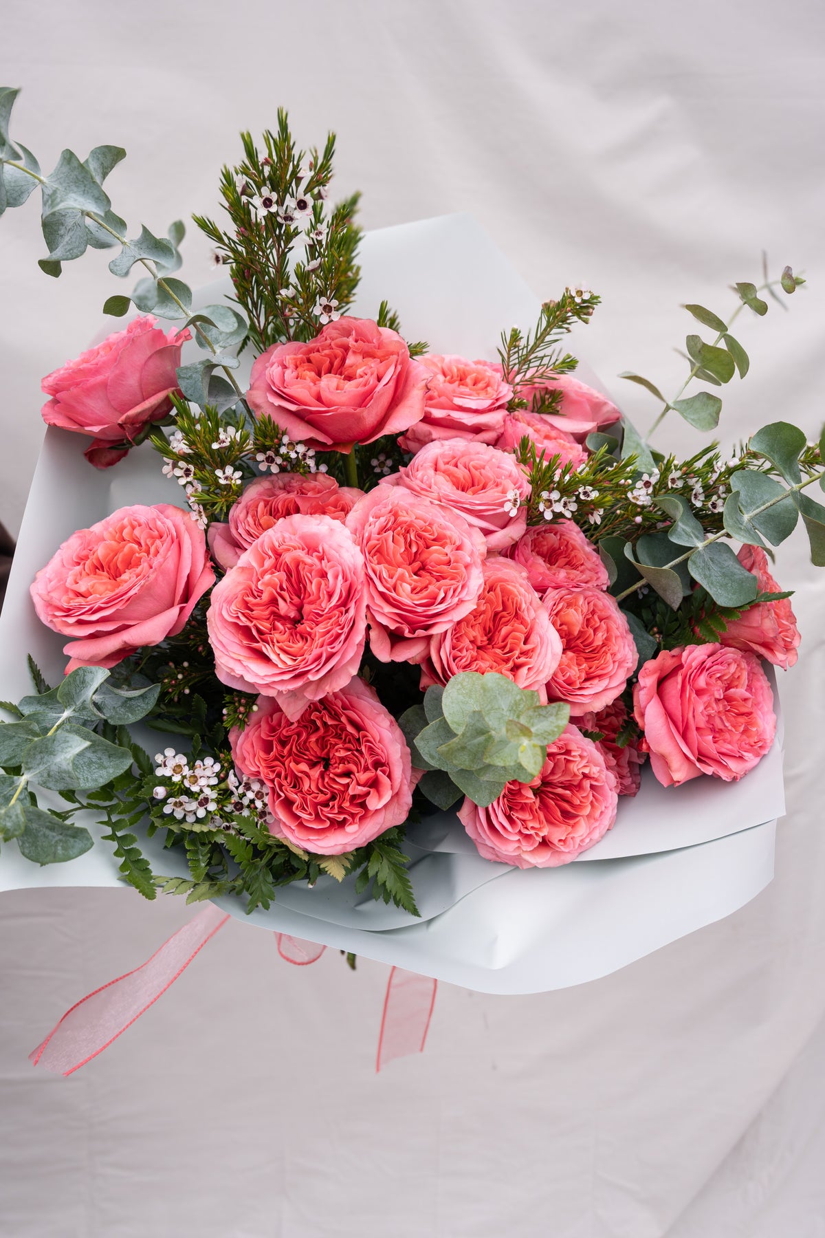 Bouquet of pink roses with greenery on a light background