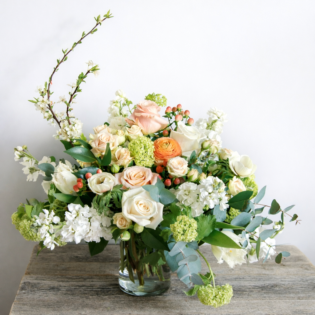 Bouquet of flowers in a clear vase on a wooden surface with a light background