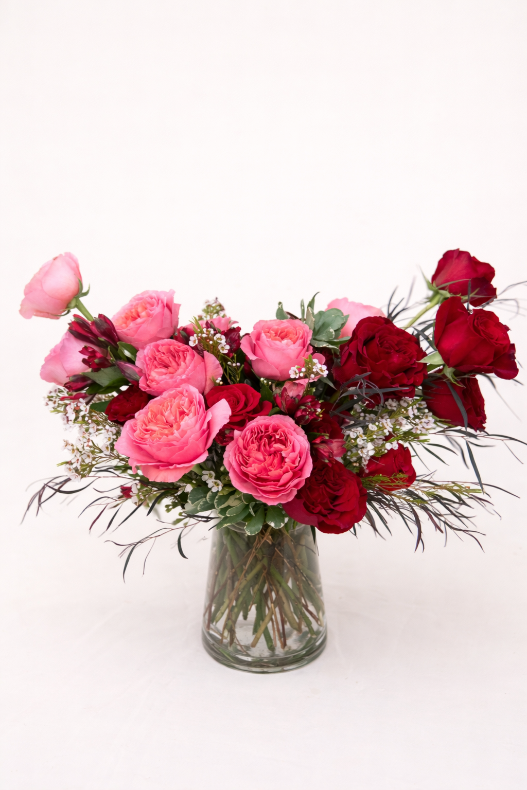 Bouquet of pink and red roses in a clear vase on a white background