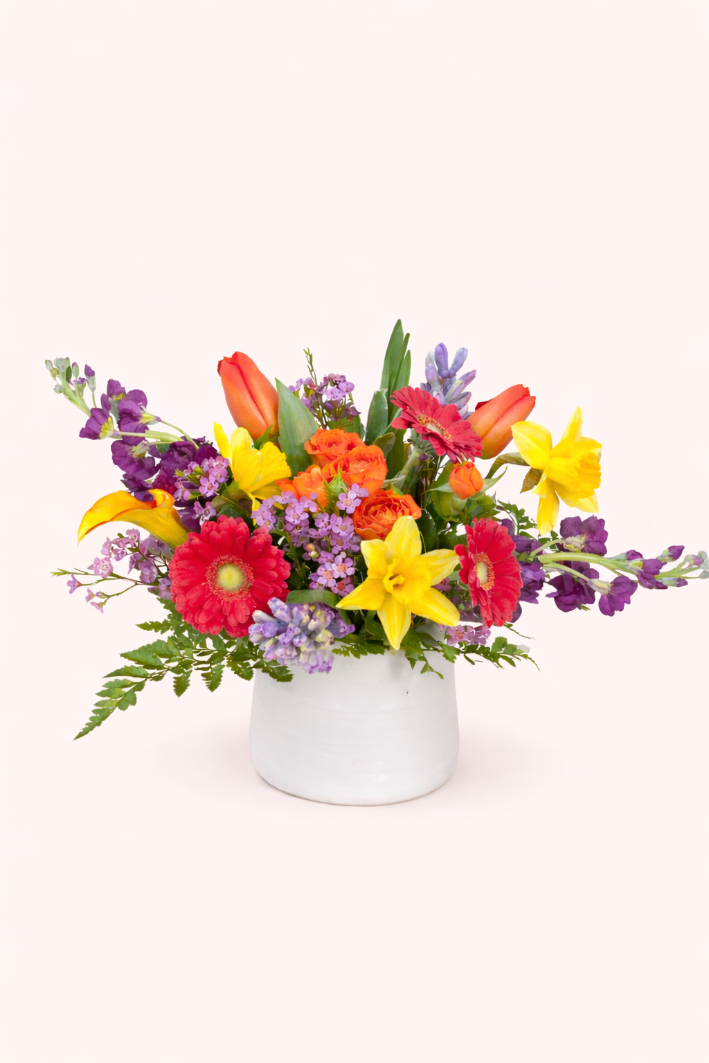Colorful flower arrangement in a white vase on a white background